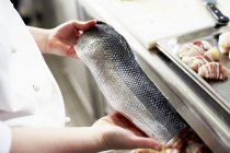 Chef tenant un filet de poisson cru — Photo de stock