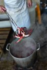 Улучшенный вид человека, держащего вареного осьминога на скиммере над парящим котлом — стоковое фото