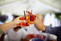 People clinking with glasses of Campari — Stock Photo
