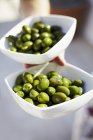 Hand hält Schalen mit grünen Oliven — Stockfoto