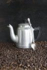 Кофейный кувшин и ложка на кофейных зерен — стоковое фото