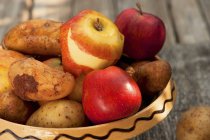 Potatoes and apples in ceramic dish — Stock Photo
