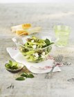 Green asparagus salad with sesame seeds and mint in glass bowl over towel with fork — Stock Photo