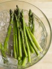 Green asparagus in iced water — Stock Photo