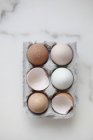 Цілі яйця та яєчна шкаралупа в коробці — стокове фото