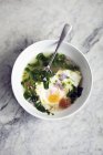 Суп с пандусами и яйцом на белой тарелке с ложкой — стоковое фото
