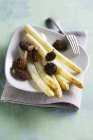 Fried asparagus with morel mushrooms on white plate  over towel — Stock Photo
