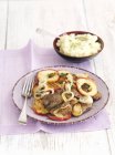 Foie de poulet frit aux pommes, oignons et purée de pommes de terre sur assiette violette avec fourchette sur serviette — Photo de stock