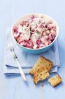 Closeup view of herring fish salad with beetroot, apple, red onions and mayonnaise in blue bowl over towel — Stock Photo