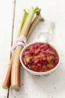 Chutney de ruibarbo con cebollas rojas, pasas, pimienta rosa, ajo y comino en la superficie de madera - foto de stock