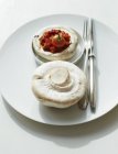 Funghi ripieni con passata di pomodoro su piatto bianco con forchetta e coltello — Foto stock