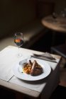 Belgian sausages with vegetable pure  on white plate over table with glass of wine — Stock Photo