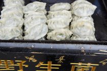 Vegetable dumplings stacked on black baking tray — Stock Photo