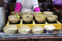 Ciotole di zuppa in un ristorante asiatico con un cuoco sullo sfondo — Foto stock