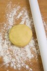 Elevated view of shortcrust pastry and a rolling pin on a floured surface — Stock Photo