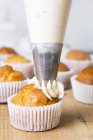Muffin being decorated with pipped buttercream — Stock Photo