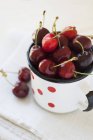 Cherries in enamel mug — Stock Photo