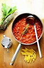 Bolognese sauce in pan near penne pasta — Stock Photo