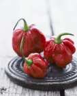Three Habaneros on small platter over wooden surface — Stock Photo