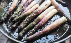 Friggere gli asparagi in una padella con olio — Foto stock