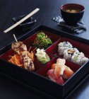 Nahaufnahme von Hühnerspieß, Nigiri und Maki-Sushi in quadratischer lackierter Schachtel — Stockfoto
