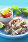 Ceviche with salsa and limes on blue plate — Stock Photo