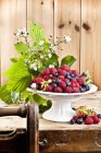 Raspberries and blueberries on cake stand — Stock Photo