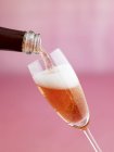 Derramando um copo de vinho espumante rosa — Fotografia de Stock