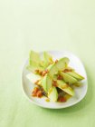 Abacate com salsa picante na placa branca sobre a superfície verde — Fotografia de Stock