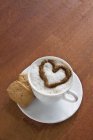 Підвищений вид на чашку кави, прикрашену молочним пінистим серцем — стокове фото