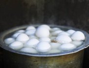 Vista de cerca de huevos blancos hirviendo en maceta de metal - foto de stock