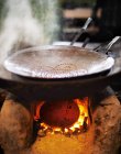 Closeup view of a steaming pan on a traditional clay stove — Stock Photo