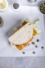 Ein Fischfingersandwich mit Tartarensauce und Kapern auf Papier — Stockfoto