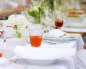 Vista de cerca de la mesa colocada con flores y bebidas - foto de stock