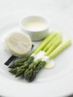 Asperges vertes avec sauce hollandaise sur assiette blanche — Photo de stock