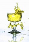 Vista de cerca de la bebida amarilla salpicando desde un vaso - foto de stock
