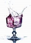 Vista de perto da bebida roxa salpicando de um copo — Fotografia de Stock