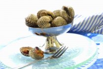 Крупный план кучи моллюсков в серебряном блюде с открытым вилкой — стоковое фото
