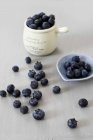 Blueberries in mug and small bowl — Stock Photo