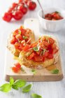 Bruschetta with cherry tomatoes and basil on wooden desk — Stock Photo