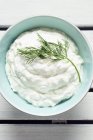 Greek tzatziki dip in blue plate over wooden surface — Stock Photo
