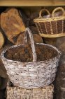 Vista diurna de una cesta de mimbre rústica llena de conos de pino frente a un cobertizo de madera - foto de stock