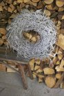 Daytime view of a woven wreath on a bench against a wood pile — Stock Photo