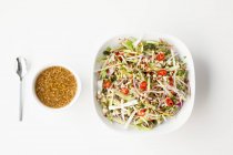 Тайский овощной салат с чесночным соусом на белой тарелке на белой поверхности — стоковое фото