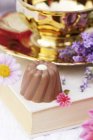 Closeup view of chocolate Praline with white decorations on book by brass bowl — Stock Photo