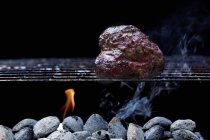 Closeup view of chicken piece on barbecue rack over embers — Stock Photo