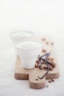 Closeup view of almond milk with vanilla pods and almonds on wooden board — Stock Photo