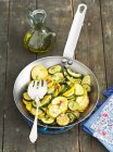 Fried courgettes with chillis on pan over wooden surface — Stock Photo