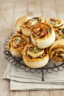 Savoury buns with dried tomato pesto and courgettes on wire rack over towel — Stock Photo
