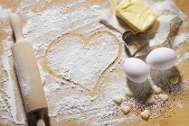 Primo piano vista di vari ingredienti da forno con mattarello e taglierine a forma di cuore — Foto stock